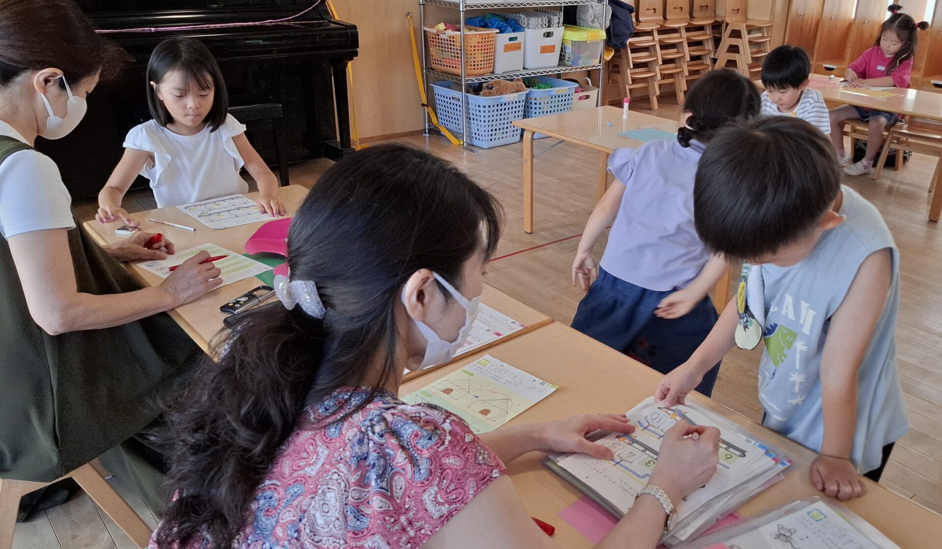 算数のお勉強をする園児と採点をする先生の写真