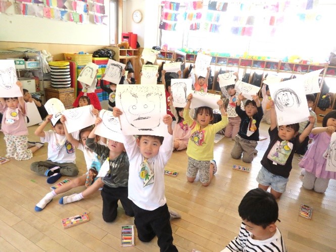 完成した自画像を見せる園児