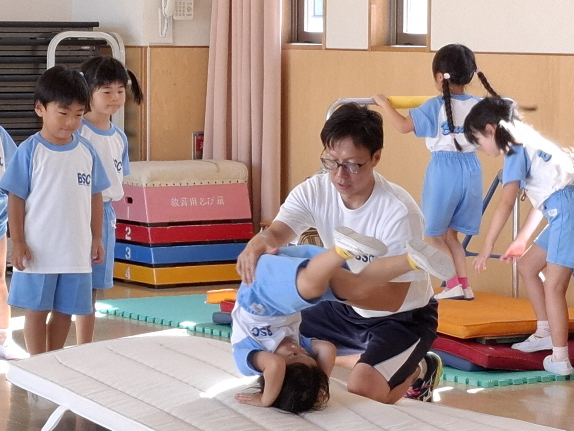 まっとででんぐり返しの練習をする園児と補助する先生