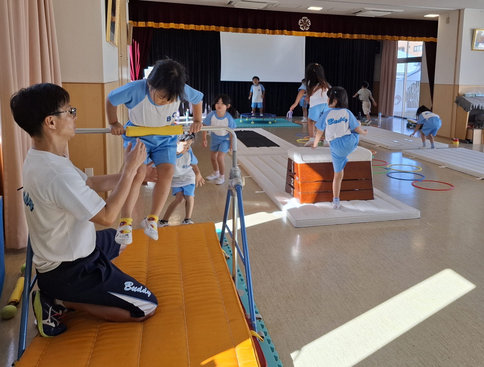 鉄棒を練習する園児と未摩耗r先生の写真